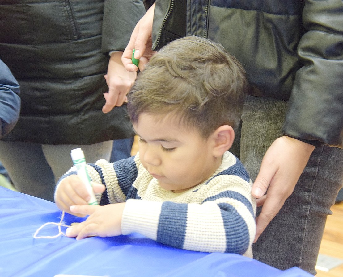 Franco Munguia, a 2-year-old who lives on Valley Terrace, is deep in concentration as he colors a Christmas tree decoration.