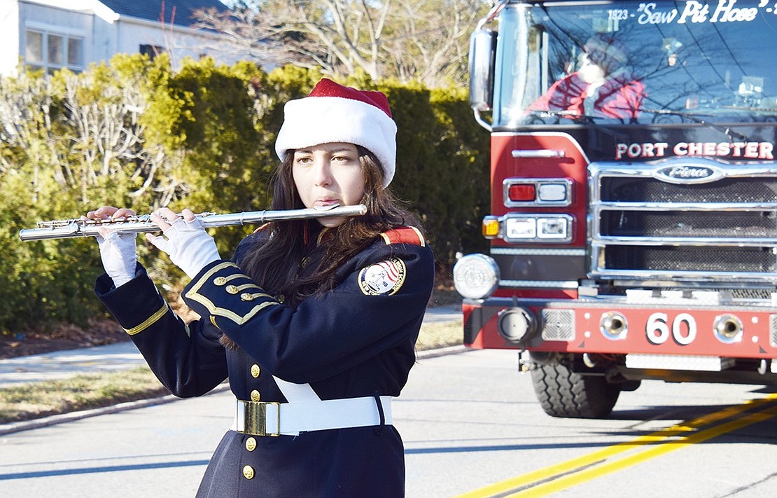 Pride of Port Chester flute section leader Natalia Fiallos, a senior, marches ahead of the firetruck carrying Santa Claus.