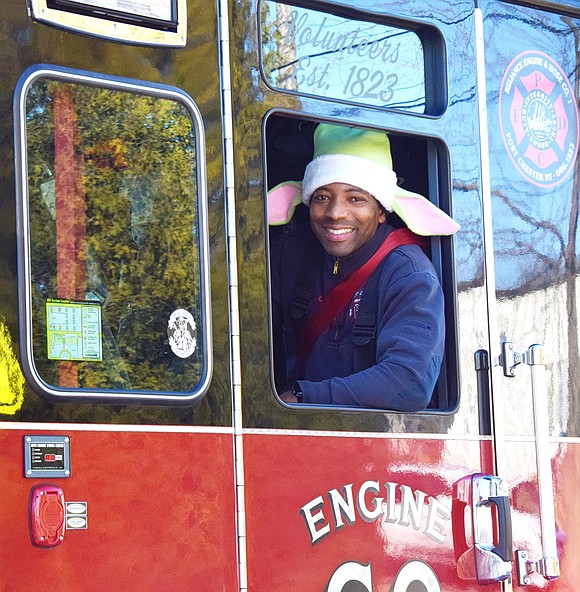 Jay Salmon of Reliance Engine & Hose Company No. 1 smiles while dressed as an elf in the rear of the truck carrying Santa Claus.