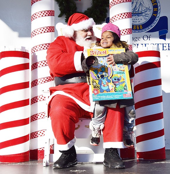 Santa Claus (who sometimes goes by Charlie Sacco) asks Grace Church Street resident Mia Cando, 5, if she’s been nice this year.