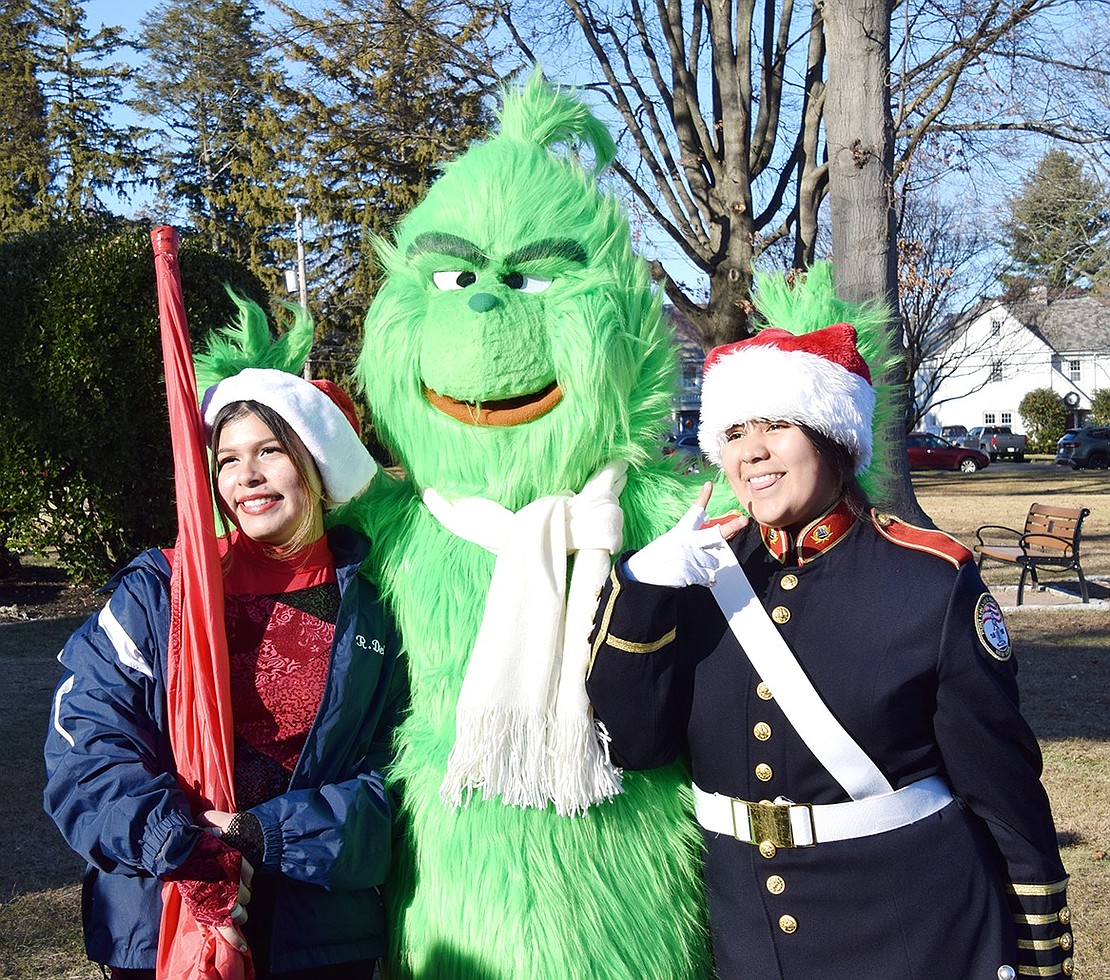 Pride of Port Chester junior color guard Allison Delgado (left) and junior drum major Sofia Coyt pose with the mischievous Grinch (played by Traci Iorio of Funtime Amusements, a Yorktown Heights-based company).