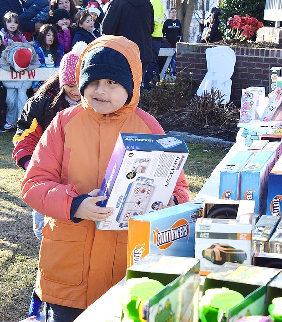 Leonardo Peña, a 9-year-old who lives on South Ridge Street, selects an air hockey toy from the gifts provided by the Village of Port Chester before making his way to meet Santa Claus.