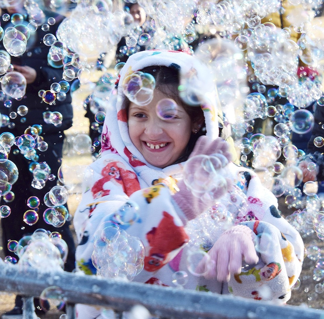 Maple Place resident Marci Jesurun, 8, gets covered in bubbles that float around a section of Lyon Park during the Santa in the Park event on Saturday, Dec. 14. Hundreds flocked to the park to receive a gift and meet Kris Kringle after he rode down King Street in a firetruck during a parade leading up to the festivities.