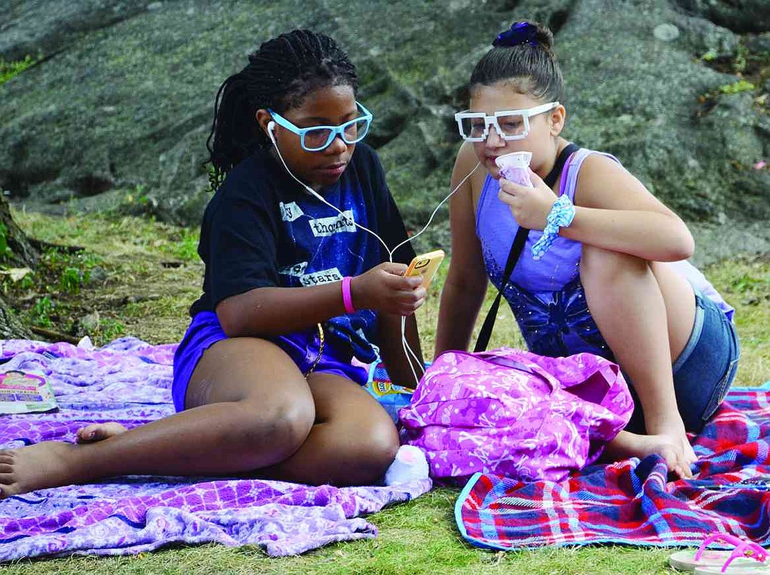 Two girls share a pair of earbuds as they listen to music at Unity Day at Columbus Park on Saturday, Aug. 9. 