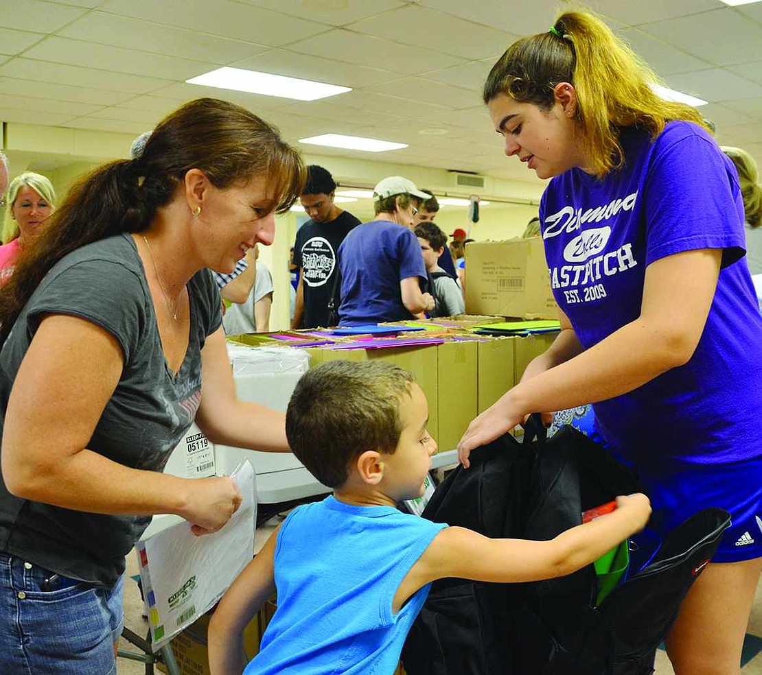 Binder dividers in hand, Liz Savino of Jennifer Lane and her 5-year-old son Nico, who passed out index cards, help fill the two backpacks 15-year-old Emma Stracuzzi of Madison Avenue carried down the assembly line.  <BR><BR> Volunteers packed 1,040 backpacks with 19 name-brand, age-appropriate school supplies at the backpack drive organized by Helping Hands for the Homeless & Hungry on Tuesday, Aug. 19 at Church of the Resurrection in Rye.     