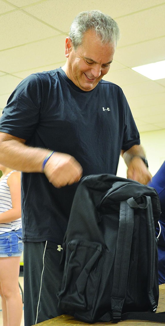 John Kiyak from the Port Chester-Rye Brook Rotary Club zips up one of the filled backpacks.  <BR><BR> Volunteers packed 1,040 backpacks with 19 name-brand, age-appropriate school supplies at the backpack drive organized by Helping Hands for the Homeless & Hungry on Tuesday, Aug. 19 at Church of the Resurrection in Rye.     