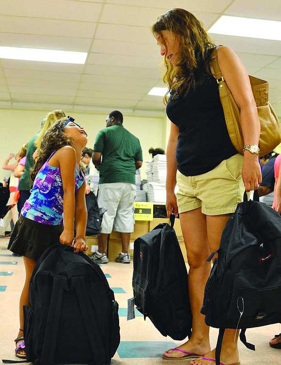 Four-year-old Camila Gonzalez of Country Ridge Drive struggles to lift up the backpack almost as big as her as she and her mother, Johnna, go to drop off the bags filled with school supplies.  <BR><BR> Volunteers packed 1,040 backpacks with 19 name-brand, age-appropriate school supplies at the backpack drive organized by Helping Hands for the Homeless & Hungry on Tuesday, Aug. 19 at Church of the Resurrection in Rye.    