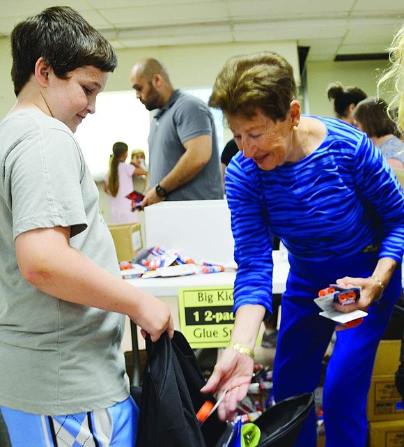 John Breslin, a 13-year-old from Woodland Drive, gets some glue sticks from Francesca Fraine of Avon Circle.  <BR><BR> Volunteers packed 1,040 backpacks with 19 name-brand, age-appropriate school supplies at the backpack drive organized by Helping Hands for the Homeless & Hungry on Tuesday, Aug. 19 at Church of the Resurrection in Rye.     
