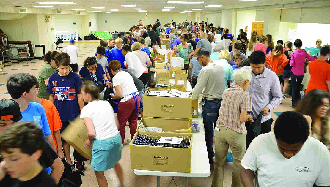 More than 100 people fill the basement of Resurrection Church in Rye to form assembly lines to fill the backpacks.  Volunteers packed 1,040 backpacks with 19 name-brand, age-appropriate school supplies at the backpack drive organized by Helping Hands for the Homeless & Hungry on Tuesday, Aug. 19 at Church of the Resurrection in Rye.   