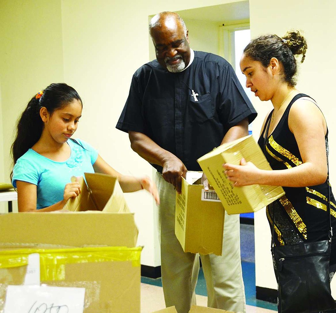 Esmeralda Salcedo, an 11-year-old from Bent Avenue, and Laura Ochoa, a 19-year-old from Bush Avenue, help Father Hilario Albert from St. Peter's Episcopal Church in Port Chester break down the empty boxes that started the day filled with school supplies.<BR><BR>Volunteers packed 1,040 backpacks with 19 name-brand, age-appropriate school supplies at the backpack drive organized by Helping Hands for the Homeless & Hungry on Tuesday, Aug. 19 at Church of the Resurrection in Rye.     