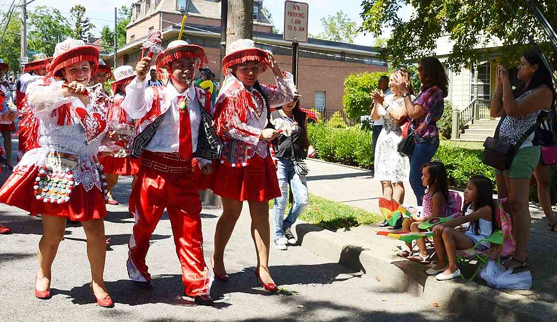 Adorned in red, Port Chester's Marcela Valdez, Jorge Pinto and Marianela Olivera from the group Kullaguada Bolivia entertain those watching on the sidewalk. 