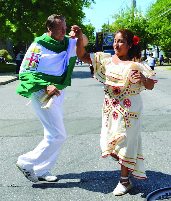 Draped in a flag, Fernando Sanguino twirls with Silvia Arroyo, also from Port Chester, as part of the Bolivian group Compara los Chichis.