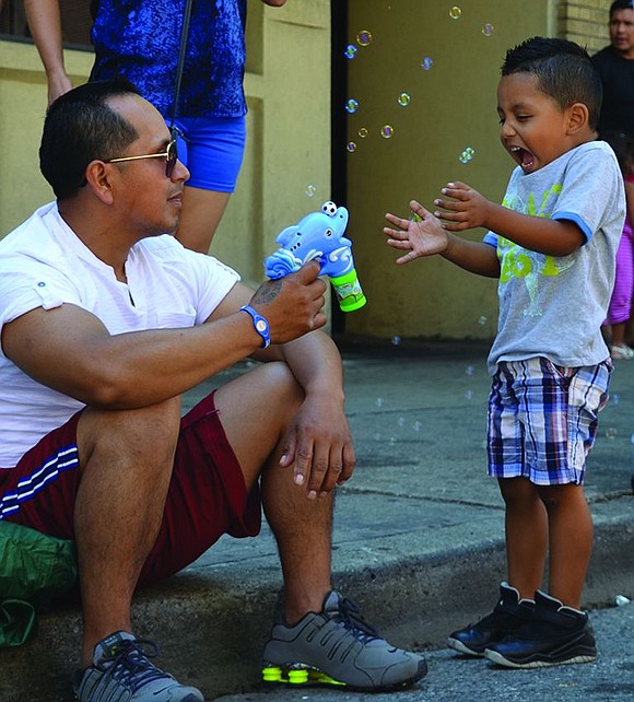 Saul Loja of Elmont Avenue sends bubbles shooting at his enthusiastic 4-year-old son Dyllen.
