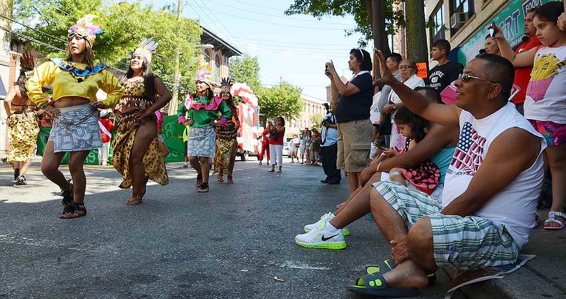 Lining the road, parade-goers snap pictures and take videos on their cell phones of Ballet Folklorico Acuarelas del Peru. 