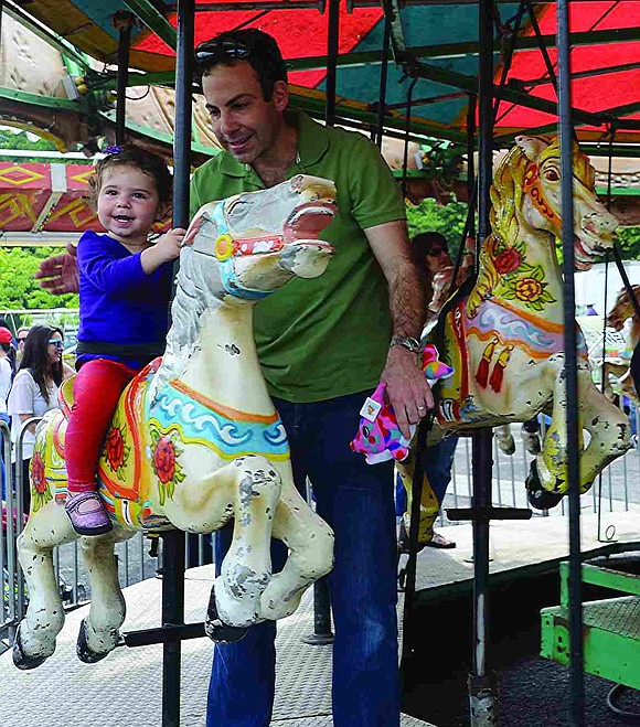  Jeff Mensch of Red Roof Drive steadies his daughter Clara, who is almost two years old, as they ride the merry-go-round. 