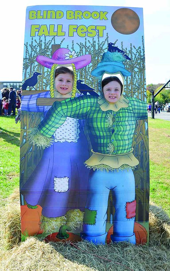 Five-year-old Chiara Fratangelo (left) of Tamarack Road and her older sister, Emilia, 7, pretend to be scarecrows. The Blind Brook PTA organized the first Fall Festival at Ridge Street School on Saturday, Oct. 25 which included a bake sale, food trucks, live music, crafts and a variety of activities for families.   