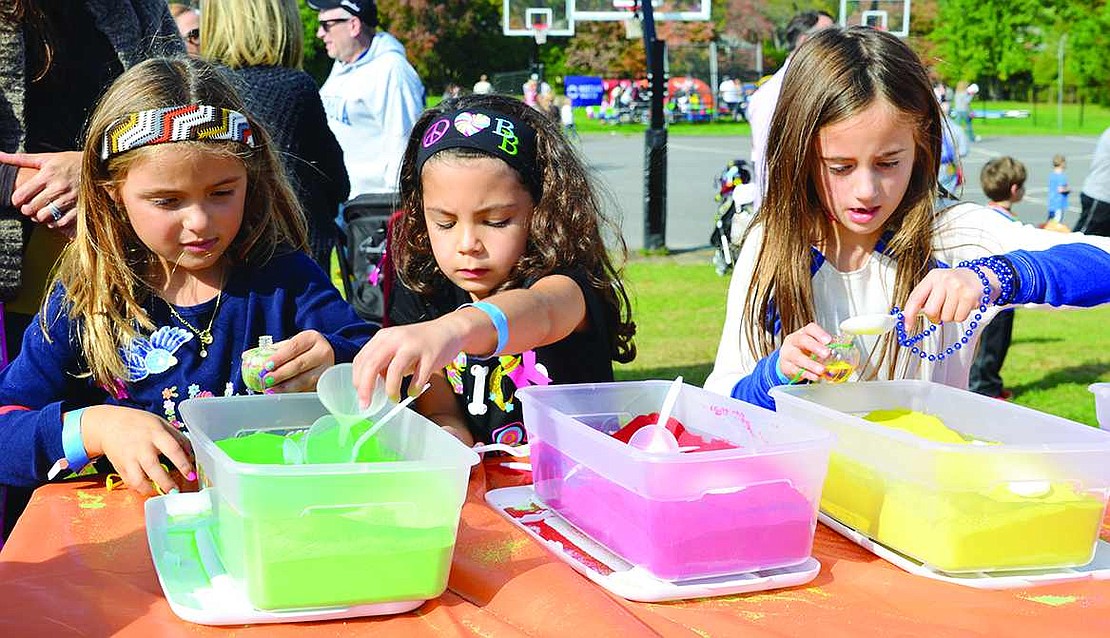 Five-year-old Sara Levine (left) of Brush Hollow Lane, 5-year-old Lyla Cotte of North Ridge Street and 7-year-old Kendall Bassett of Fellowship Lane carefully fill up tiny plastic pumpkins with layers of colored sand. 