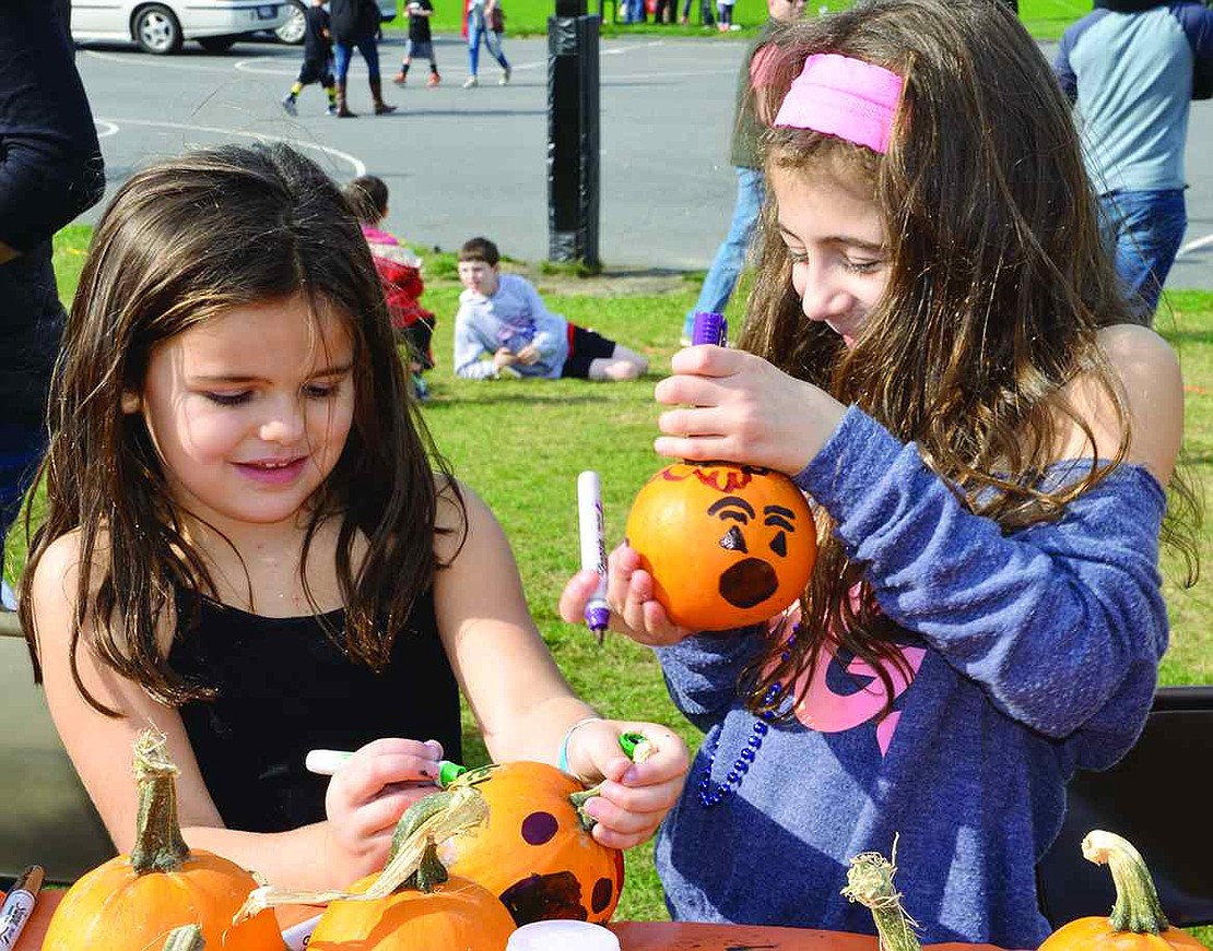 Joley Meron, 5, and Maya Vinikoor, 7, decorate pumpkins with Sharpie markers. 