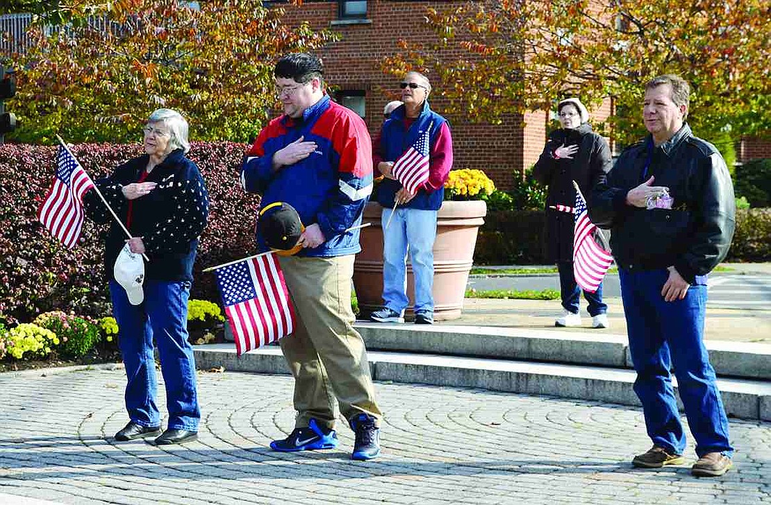  The sparse crowd that attended the ceremony holds flags and places their hands over their hearts during the Pledge of Allegiance at the Port Chester-Rye Brook Veterans Day Ceremony at Veterans' Memorial Park on Sunday, Nov. 10.