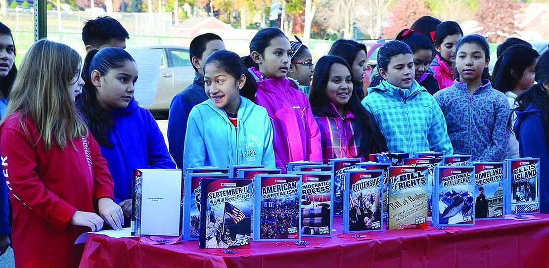  Students in Jennifer Carriero-Dominguez's class stand behind a table piled with age-appropriate history books donated by Hank and Isabelle Birdsall. The Vietnam veteran and his wife, who both worked as teachers in the Port Chester School District, started donating books several years ago in honor of local veterans who died recently. Each book has a name inscribed inside the front cover and will be placed in the Park Avenue School library for students to check out and take home. 