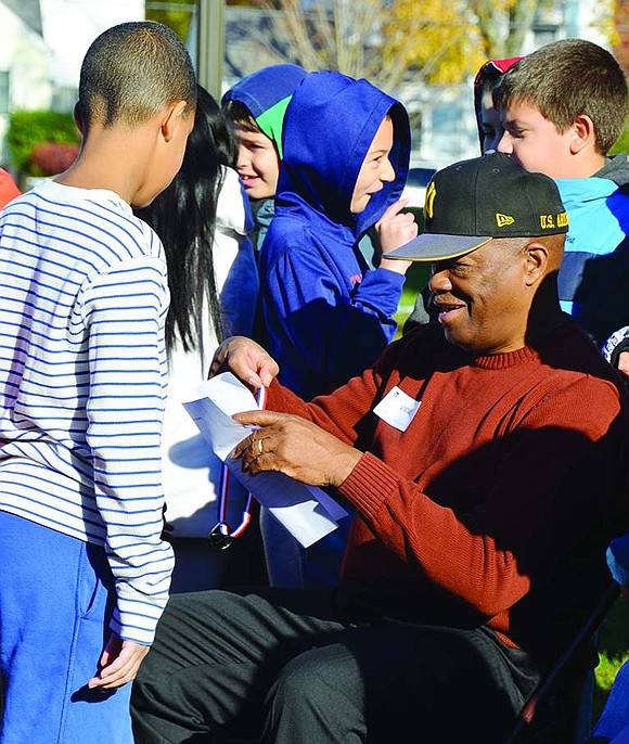  Jeremiah Riggans, an Army veteran, accepts a medal on a red, white and blue ribbon from his grandson, Keon Riggans, a Park Avenue School 5th grader. 