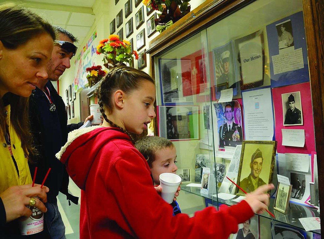  DeAnne and Jason Ostrowski, both veterans of the U.S. Navy, and their children, Madison, a 5th grader, and Tyrus, a 1st grader, look at the display in Park Avenue School's lobby showing pictures of those who served in the military. 