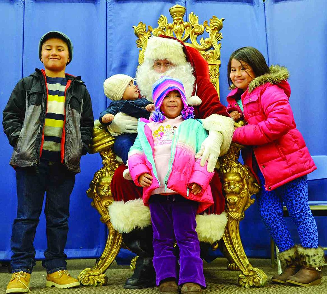 One -year-old Rileigh Chavez looks up at Santa while Rinardo, Celene and Jasmine Abdon from Ellendale Avenue crowd around. 