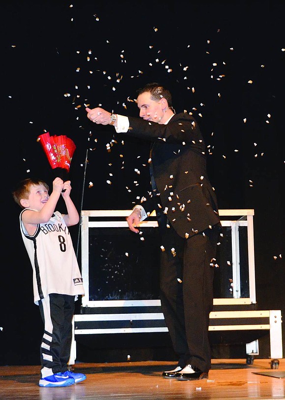  Ridge Street School kindergartner Trevor Feist fans a wet piece of paper held by magician Tom Pesce, transforming it into snow.