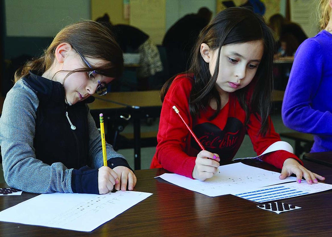  After learning how braille works, Maddie Fishback (left) and Mia Fishkind in Linda Greco's first grade class carefully color in the appropriate dots to spell their names.  