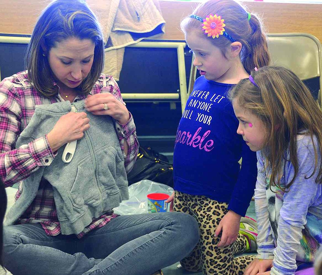  Deborah Ebenstein demonstrates for Joely Steinthal, wearing a shirt that reads "Never let anyone dull your sparkle," and Juliette Hirsh how a pull-hook can make it easier for someone with a poor grip to pull a zipper up and down. 