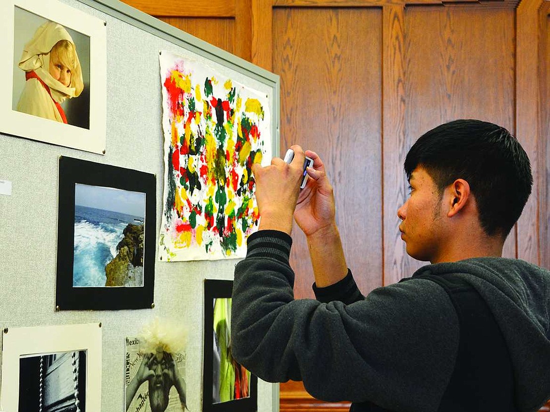  Port Chester High School senior Edin Melchor snaps a picture on his phone of a photo taken by Emily Maldonado, one of the International Baccalaureate Art students, during an art show on Thursday, Apr. 9.  