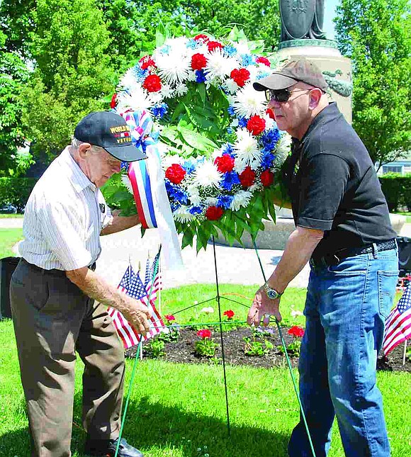 World War II veteran Joe Antalec and Pete Sileo, who served in the U.S. Army during the Vietnam War, both of Port Chester, lift one of the memorial wreaths to place in front of the World War II and Korean War monument at Veterans' Memorial Park during a ceremony on Monday, May 25.