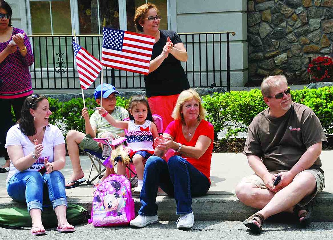 Port Chester residents smile, clap and wave flags as the Port Chester High School Marching Band goes past. From left: Kelly Castro and Kayla Castro of Haines Boulevard and April Robbins of Rex Road. 