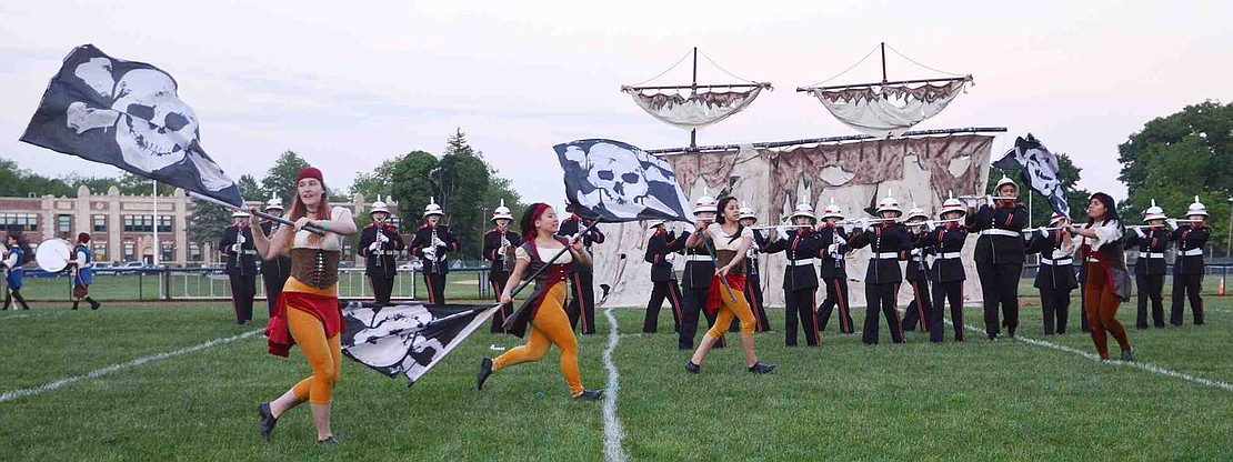 Carrying flags bearing the Jolly Roger, Christina Marquez, Dara Pecora, Kate Garcia and Marianela Olivera dance in front of the Port Chester High School Marching Band and a pirate ship during this year's field show which was Pirates of the Caribbean themed. 