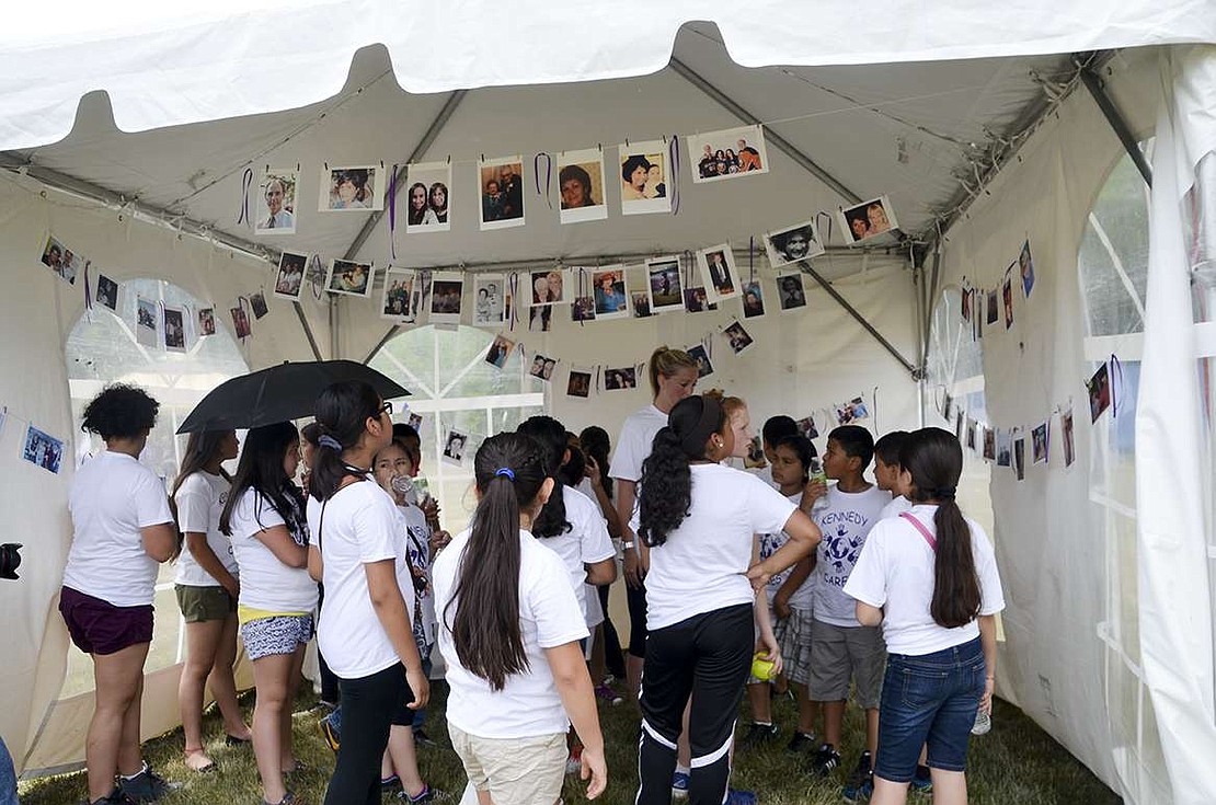 Students from the group Kennedy Cares look at the pictures of  loved ones who battled cancer in the tent of remembrance. 