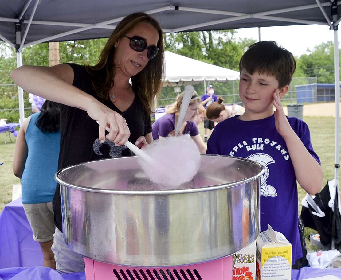 Liz Grill of Rye Brook shows Jackson Klein how to make cotton candy, something the Purple Trojans Rule team sold as part of their fundraising. 