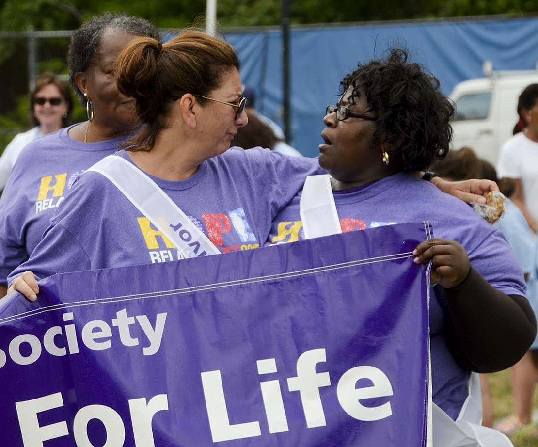 An emotional Connie Franceschini (left) and Patricia Pride hold up part of the Relay for Life banner during the lap for only survivors of cancer. Franceschini, who lives in Rye Brook, and Pride, who lives in Connecticut, grew up in Port Chester and knew each other 30 years ago. The two reunited during the survivors' lap. 