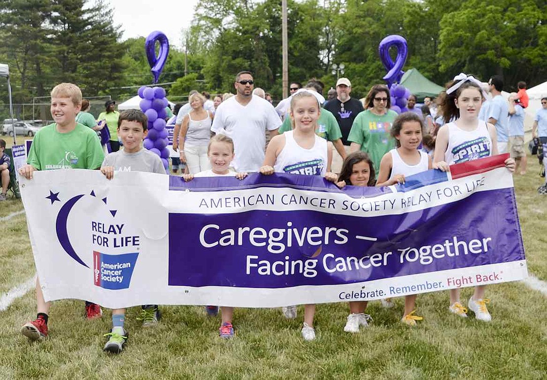 Local children, who all acted as caregivers for loved ones who fought cancer, carry a Relay for Life banner during a fundraiser at Port Chester Middle School on Sunday, May 31. 
