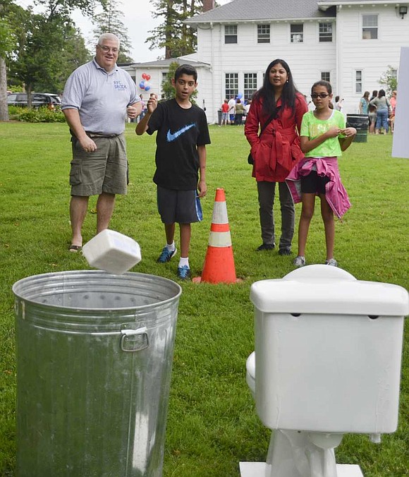 Jared Leonard, 11, of Betsy Brown Road tosses a brick into a trash can in order to win a t-shirt while his sister Karina (right), 8, and mother, Ferona, as well as Rye Brook Village Administrator Chris Bradbury (left) watch. 
