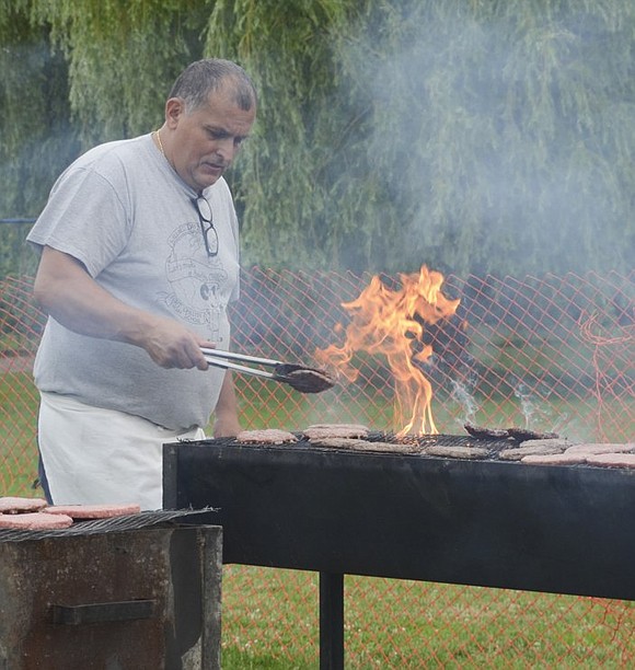 Mario DiLeo, a custodian at Port Chester Middle School, flips burgers on grills set up in Crawford Park. 