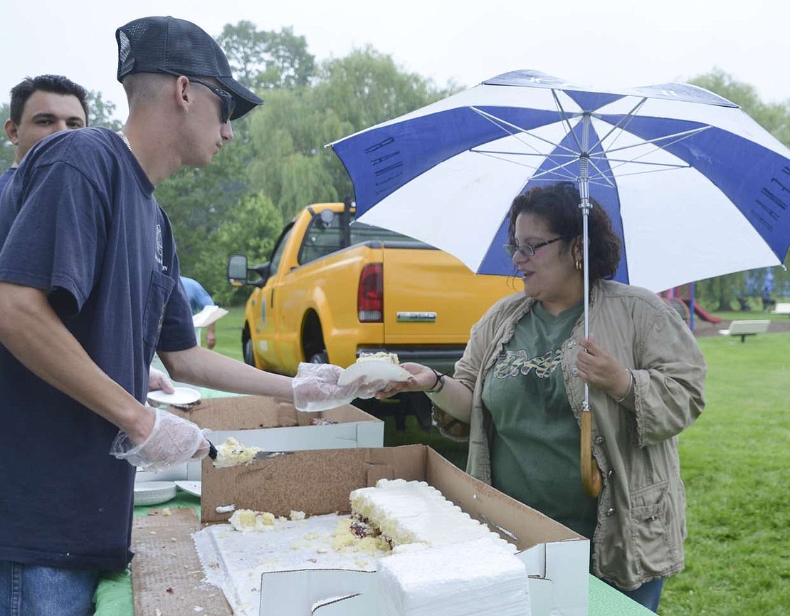 Justin DiSanto passes a slice of vanilla cake with a layer of raspberry in the middle of it to Nydia Alvarez of Port Chester. Alvarez was one of many attendees who stuck it out once the rain started on Saturday. 