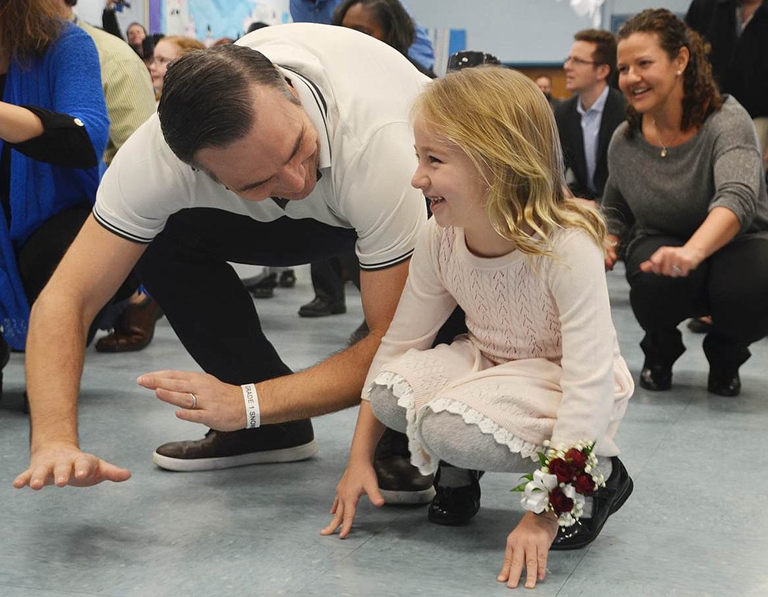 Grin on her face, Ruby McElwee and her father Stewart get as low to the floor as they can during the "Cha-Cha Slide." 