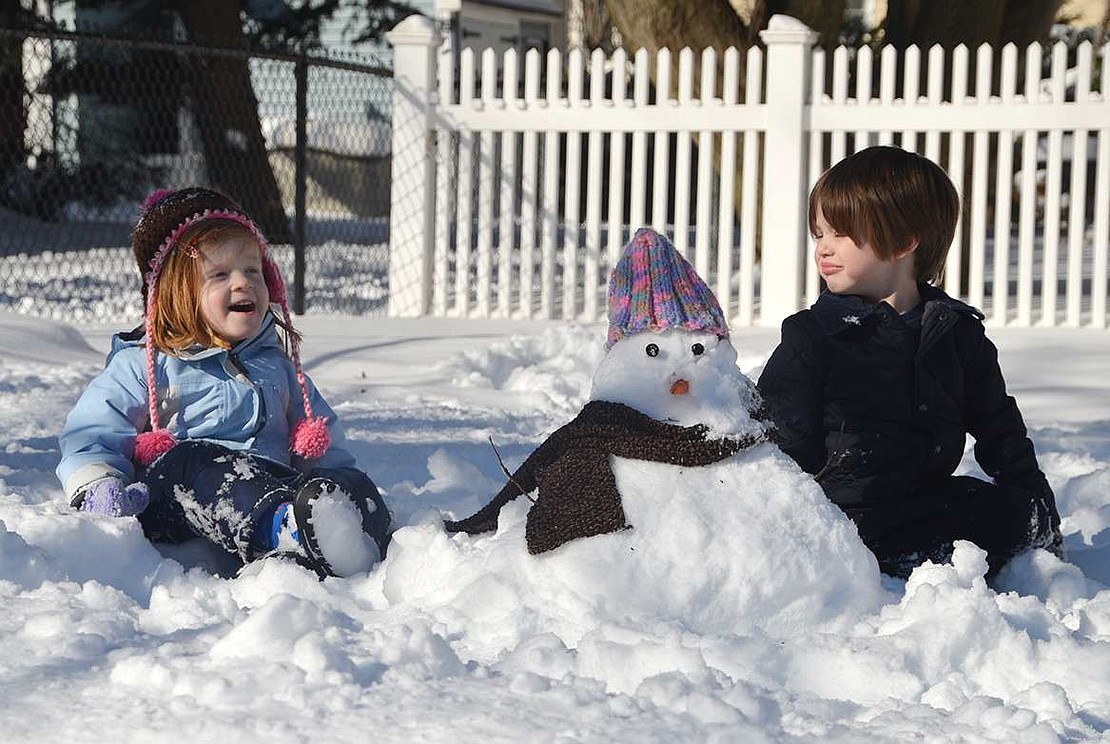 Cousins Gemma and Owen Krissoff, both 4, plop down in the snow adjacent to the snowman they made in their front yard on Adams Avenue.