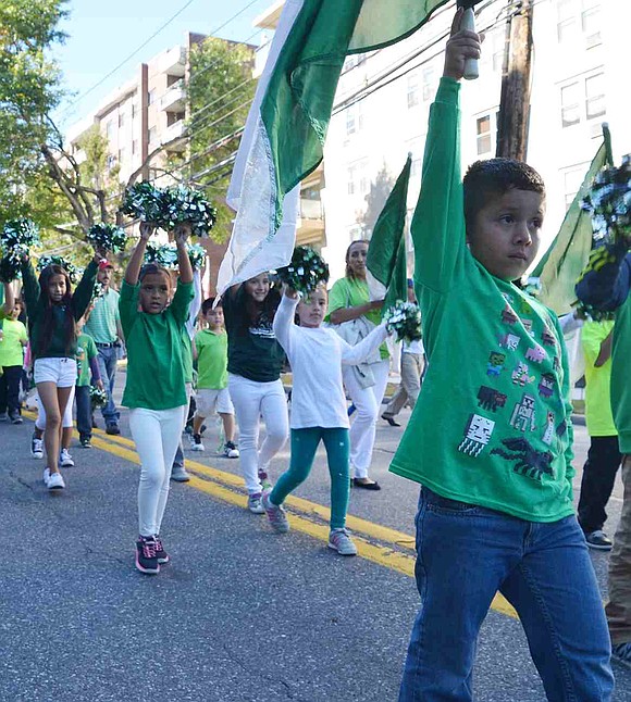 In green and white, Edison School students stride down the street. 