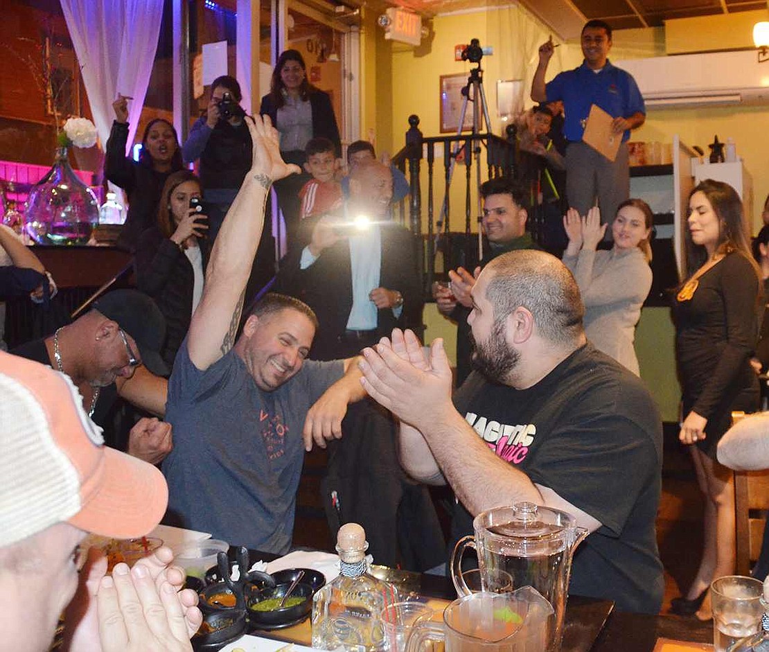 Jon Lovallo of Port Chester raises his arm in victory. He, as well as Jake Lopez of Pearl River, seated next to him, tied for first place in the contest after each consuming 24 tacos in half an hour. 