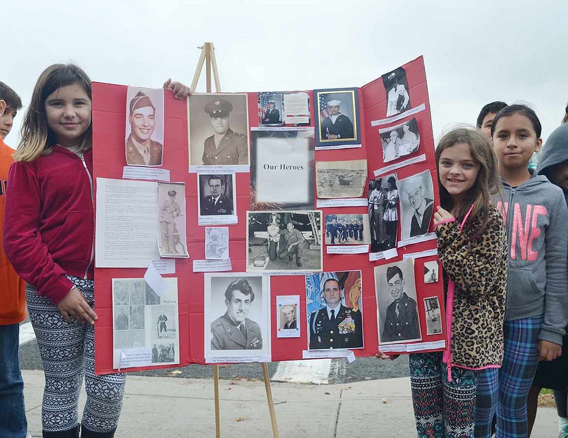  Park Avenue School fifth graders Laysa Eboli (left) and Marissa Luchen hold a poster with pictures of veterans on it. 
