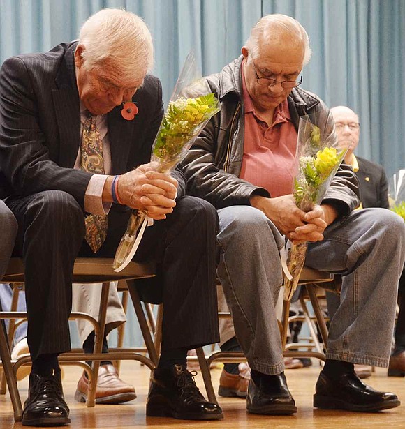  Two men bow their heads while a list of deceased veterans is read out loud. John Holt, who wore a red poppy on his lapel, served for 25 years in the British Royal Navy, and Nicholas Gaglia flew B-52s for the U.S. Air Force during the Vietnam War. 