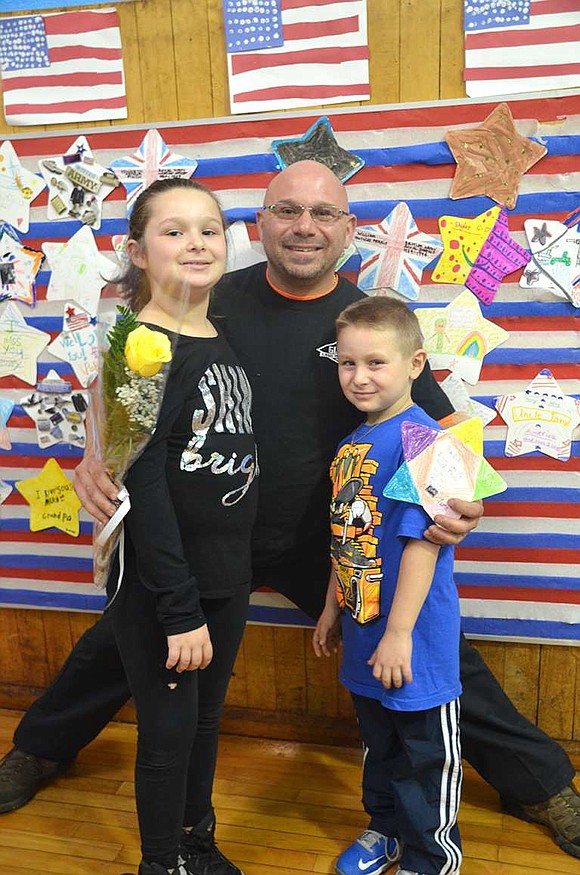  Paul DiMeglio, who served with the U.S. Marine Corps, poses with his daughter, Gianna, a 4th grader, and son, Luca, a 1st grader, in front of a wall of stars, each one made for a different veteran. 