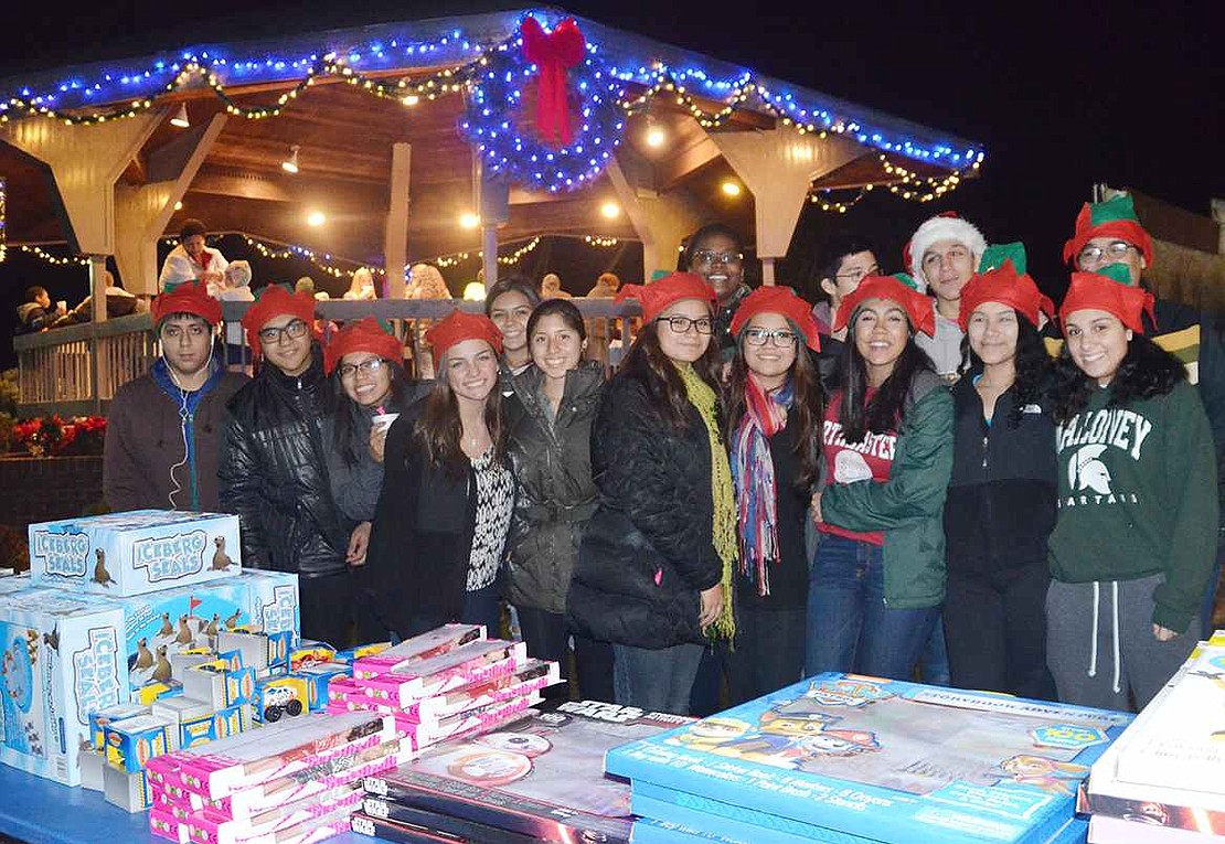 Elf hats on their heads, Port Chester High School students prepare to help hand out presents to the many children gathered at Lyon Park.   