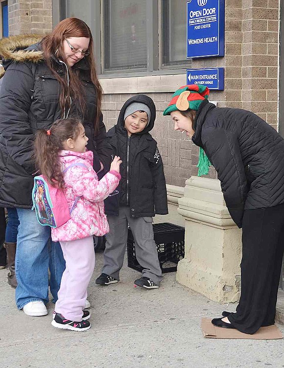  Elf hat on her head, Leanna D'Agostino, an AmeriCorps member, greets Gianna Arroyo and Alexis Gonzalez. The two Port Chester four-year-olds, as well as Kelly Misiewicz, were some of the many people waiting in line to see Santa at Open Door.  